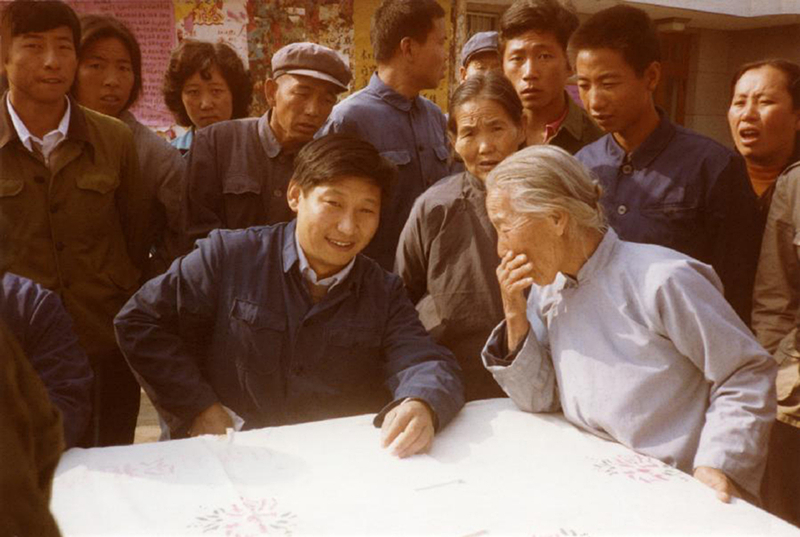1983年，時(shí)任河北正定縣委書記的習(xí)近平（前排居中），臨時(shí)在大街上擺桌子聽取老百姓意見。